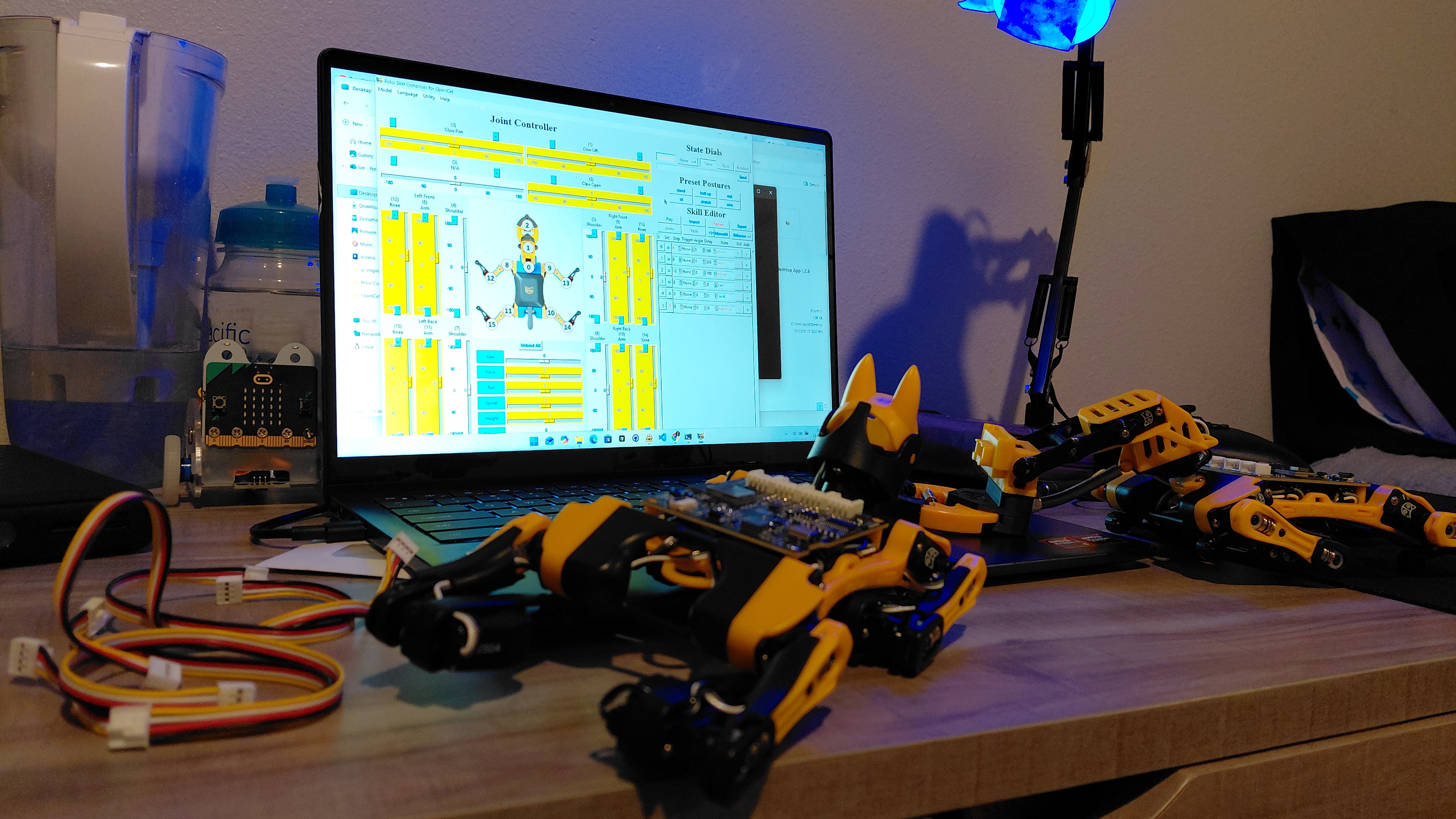Laptop with robot control software and a small yellow quadruped robot on a desk