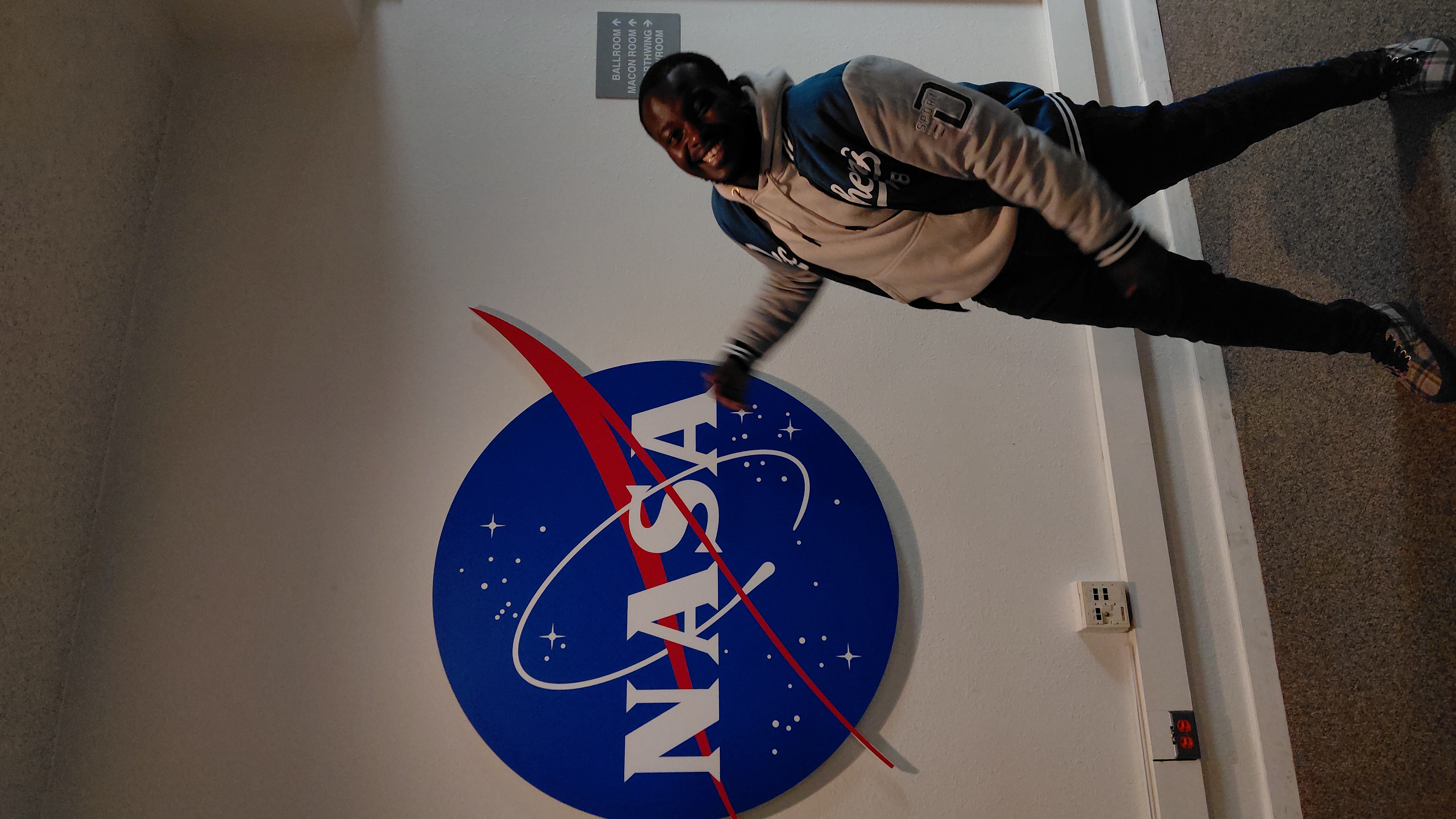 Ian posing next to a large NASA logo at an indoor event